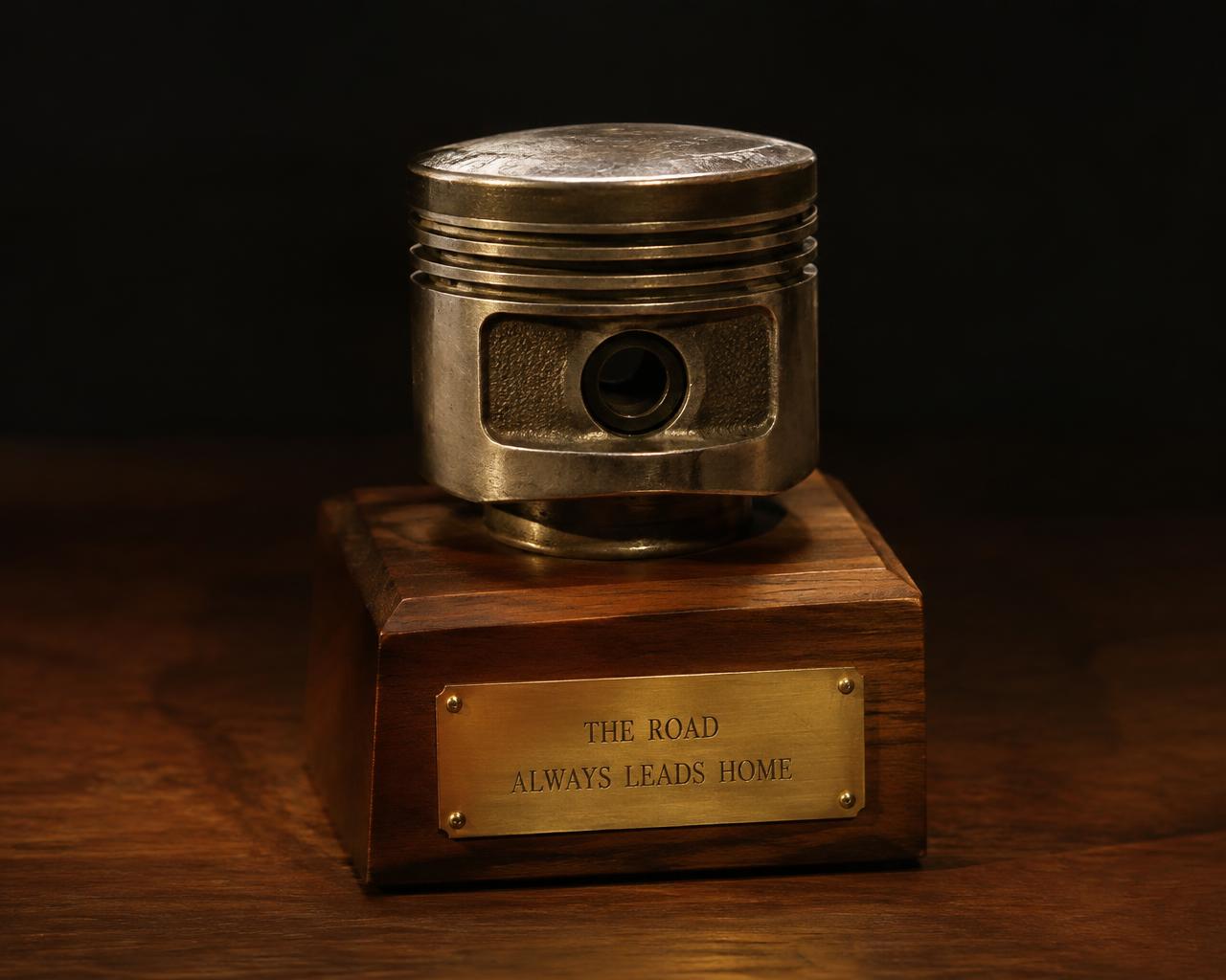 A vintage piston mounted on a walnut base with an engraved brass plate